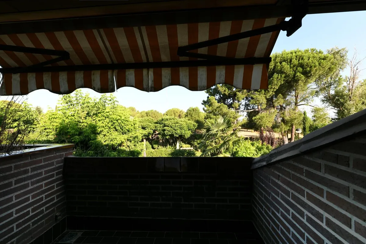 Store banne à toile rayée orange et blanche déployé au-dessus d'une terrasse en briques